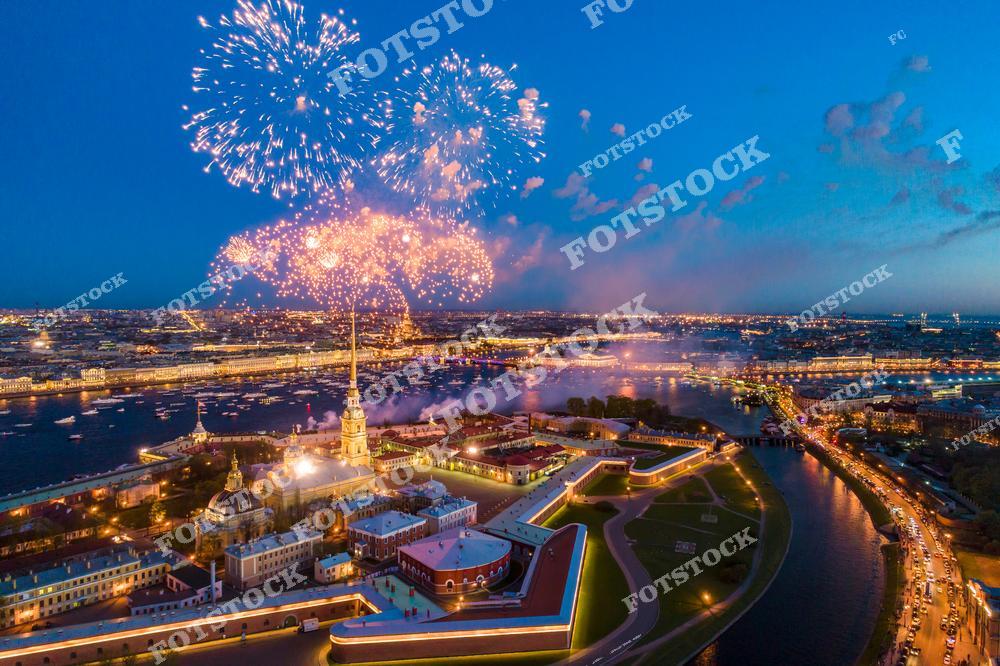 На фотографии запечатлен яркий фейерверк над Петропавловской крепостью в Санкт-Петербурге. Вечерний город и подсвеченные набережные реки Невы создают атмосферу торжества. Центральное место занимает шпиль Петропавловского собора, окруженный светом иллюминации и праздничным настроением. Этот вид отражает магию ночного Петербурга во время праздничных мероприятий.